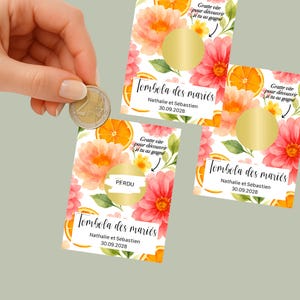 Peut inclure: Trois cartes à gratter florales avec des fleurs à l'aquarelle, des tranches d'orange et des zones à gratter dorées. Le texte comprend "Tombola des mariés" et la date 30.09.2028. Une main tient une pièce de monnaie à côté.
