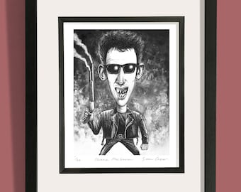 May include: Black and white caricature print of a man in sunglasses holding a smoking object. The print is framed in a black frame with a white mat. The print is signed by Shane MacGowan and Simon Cooper.