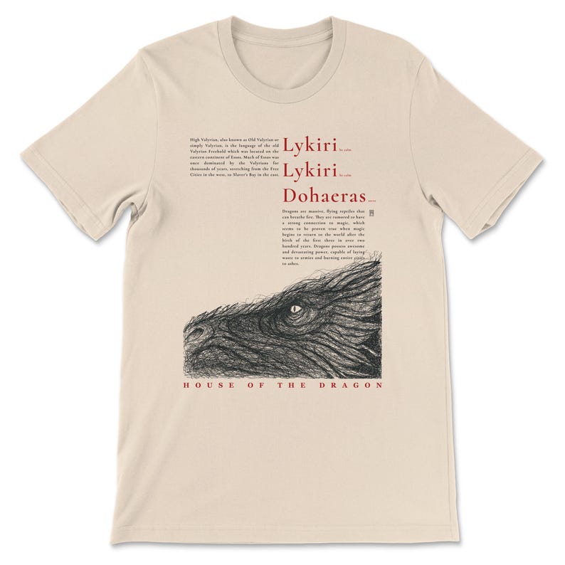May include: Beige t-shirt with a black and white dragon illustration and text. The text includes "Lykiri", "Dohaeras", and "House of the Dragon". The shirt is made of a soft material.