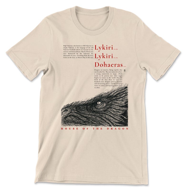 May include: A beige t-shirt with a black and white dragon illustration. The design includes the words "Lykiri, Lykiri, Dohaerus" and "House of the Dragon" in red and black text. The shirt is a neutral colour.