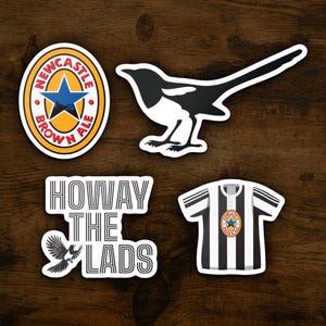 Op de afbeelding: Vier stickers met Newcastle Brown Ale branding. De stickers zijn zwart-wit en bevatten een ekster, een voetbaltenue, een logo en de zin "Howay the Lads".