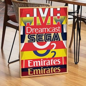 May include: A framed poster with a colorful design featuring the words "Dreamcast", "SEGA", and "Emirates" repeated in different colors and sizes.