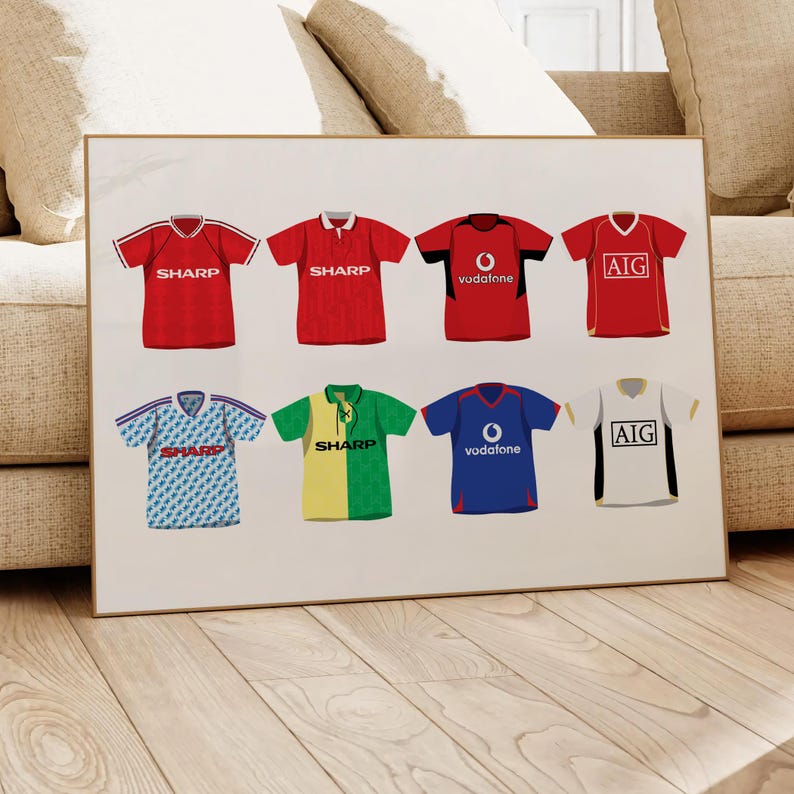 May include: A collection of eight Manchester United football jerseys, featuring different sponsors from the 1990s and early 2000s. The jerseys are red, white, blue, green, and yellow with various sponsors including Sharp, Vodafone, and AIG.