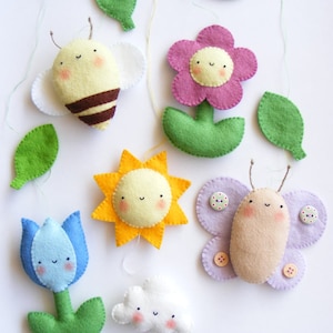 May include: A felt garland with a yellow sun, a pink flower, a blue tulip, a white cloud, a brown butterfly, and a yellow and black bee. Each felt figure has a smiling face.