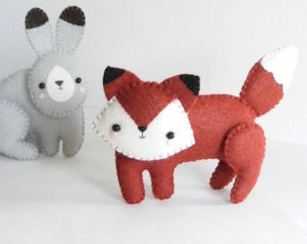 May include: A red fox and a gray rabbit plush toy. Both toys have embroidered eyes and noses. The fox has a white belly and a white tip on its tail.