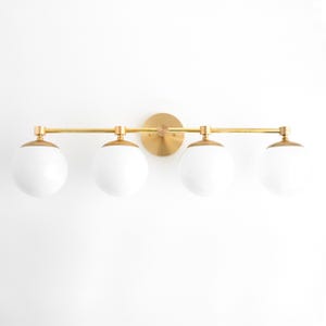 May include: A gold four-light vanity light fixture with white globe shades.