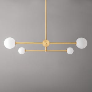 May include: A gold metal chandelier with four white globe-shaped light bulbs. The chandelier has a modern, geometric design.