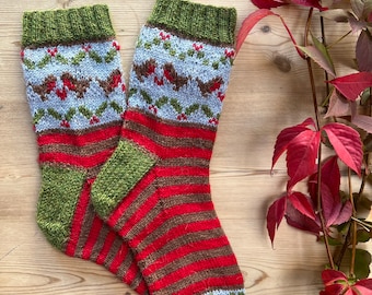 Peut inclure: Une paire de chaussettes tricotées avec un motif rayé rouge, vert et marron. Les chaussettes ont un motif de rouge-gorge et de houx en haut.