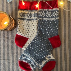 May include: A pair of knitted socks with a white and blue geometric pattern. The socks have red cuffs and heels.