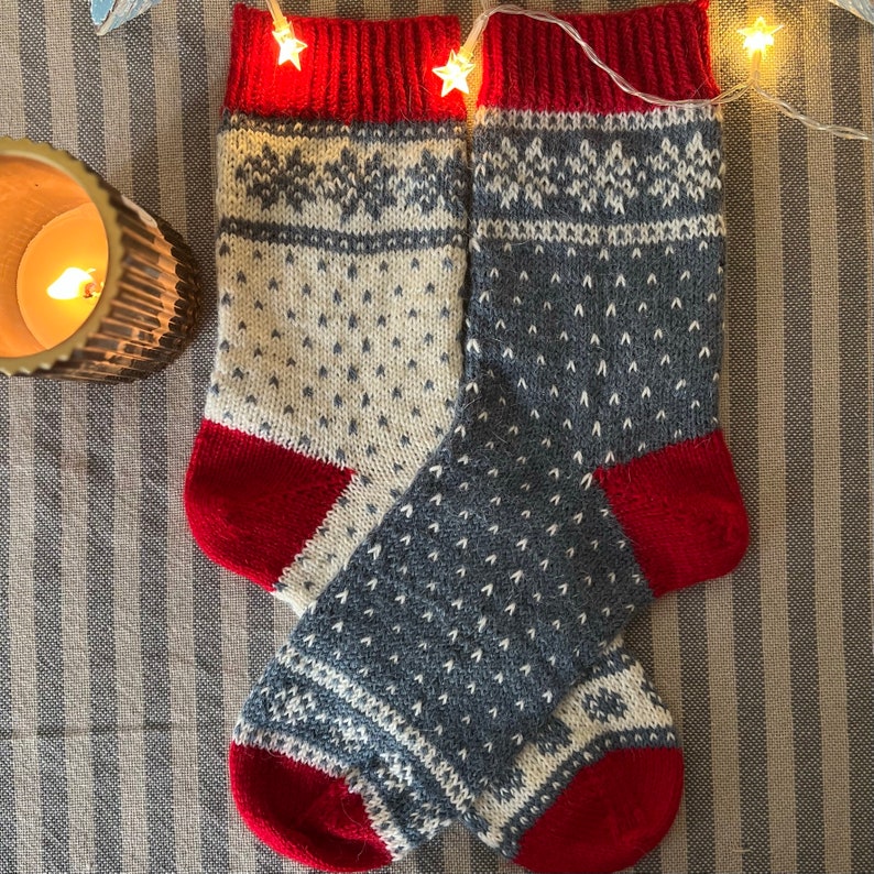 May include: A pair of knitted socks with a white and blue geometric pattern. The socks have red cuffs and heels.