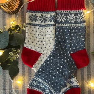 May include: A pair of knitted wool socks with a red, white and blue pattern. The socks have a snowflake design and are perfect for the winter season.