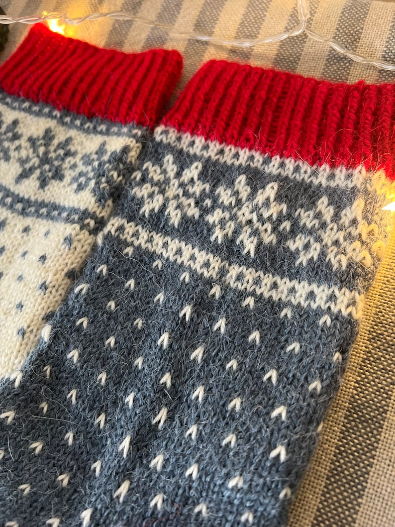 May include: A pair of knitted wool socks with a grey and white snowflake pattern and red cuffs.