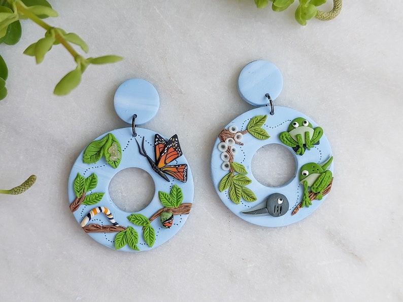 Intricately detailed handmade polymer clay earrings featuring metamorphosis -- a butterfly life cycle on one earring and a frog life cycle on the other.
