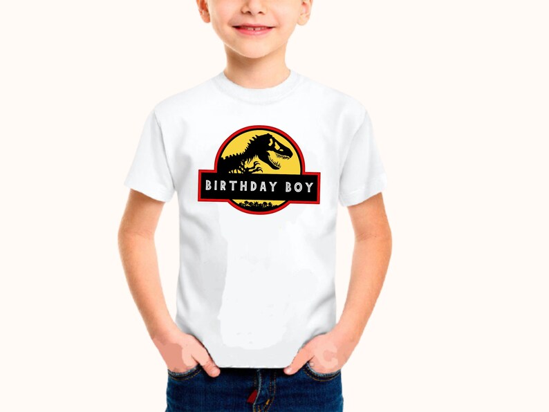 May include: White t-shirt featuring a black dinosaur graphic and the text "Birthday Boy" in a red box.