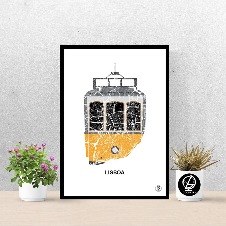 May include: A black framed print of a yellow tram with a map of Lisbon, Portugal, inside. The tram is outlined in black and the map is in shades of gray. The word "LISBOA" is printed in black at the bottom of the print.