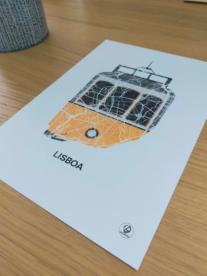 May include: A white print with a yellow and black tram design. The tram is made up of the city map of Lisbon, Portugal. The print has the word "LISBOA" and a small logo at the bottom.