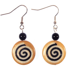 May include: A pair of earrings with a black bead and a wooden disc with a white and black spiral design.