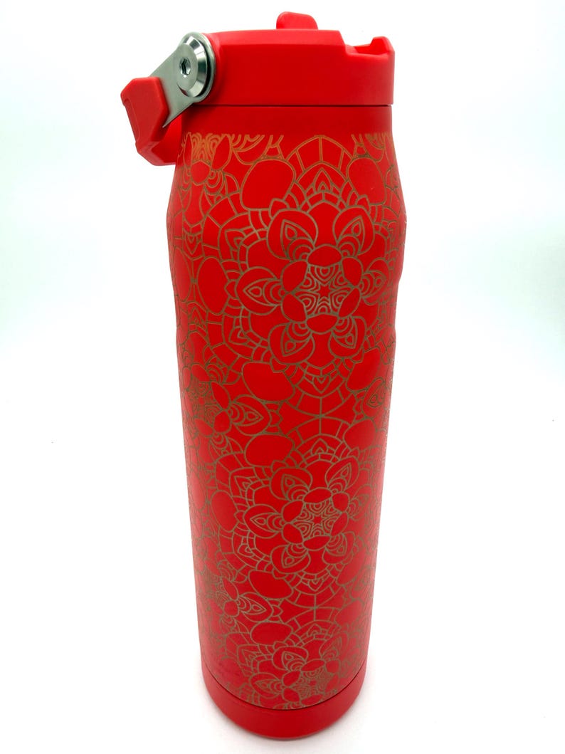 May include: A red insulated water bottle with a gold mandala pattern. The bottle has a flip-top lid and a handle. The bottle is approximately 10 inches tall.