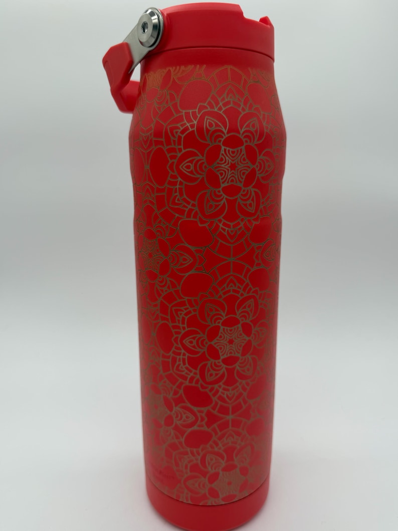May include: A red insulated water bottle with a gold mandala pattern. The bottle has a red lid with a silver hinge and handle. The bottle is approximately 10 inches tall.