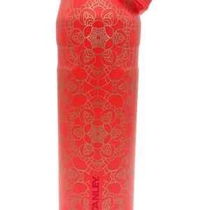 May include: Red insulated water bottle with a gold mandala pattern. The bottle has a red lid with a flip-top straw and a metal handle. The Stanley logo is visible on the side.