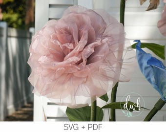 May include: A large, light pink paper flower with delicate, layered petals. The flower is mounted on a green stem with green leaves. The image also includes a blue and green flower. The text "SVG + PDF" is visible at the bottom.