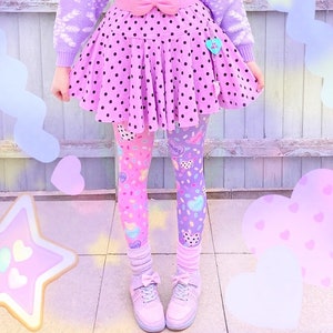 May include: A pastel-themed outfit featuring a lavender sweater with snowflake patterns, a pink polka-dot skirt, and color-blocked leggings. The ensemble includes a pink bow belt, matching shoes, and decorative accessories. The overall aesthetic is whimsical and playful.