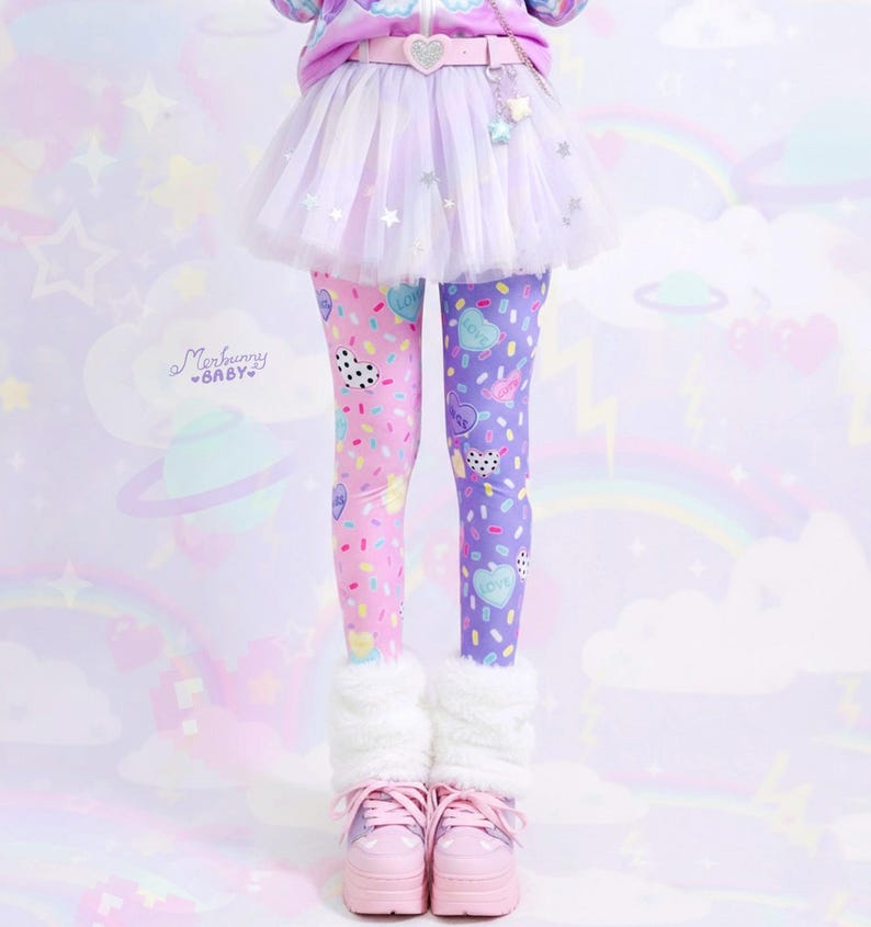 May include: A whimsical outfit featuring split-color leggings, one leg pink and the other purple, adorned with heart and sprinkle patterns. The ensemble includes a white tulle skirt, a pink belt, and platform sneakers. The look is completed with fluffy white leg warmers.