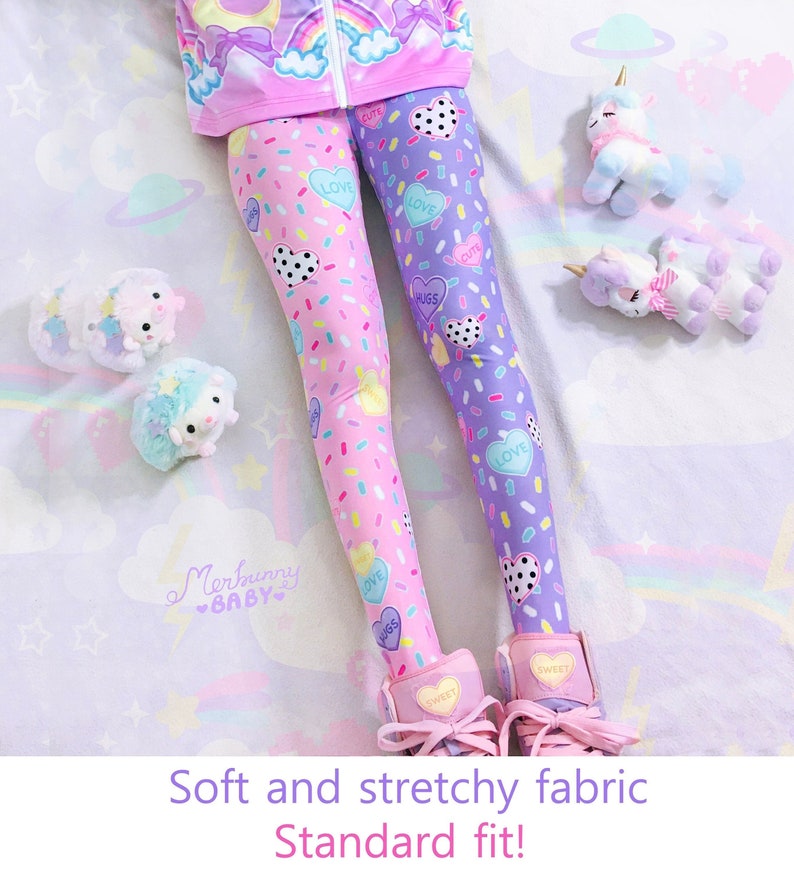 May include: Pink and purple leggings with a candy and heart pattern. The leggings have the words "LOVE", "HUGS", and "CUTE" on them. The image also shows plush unicorn and hedgehog toys. The text on the image says "Soft and stretchy fabric Standard fit!"