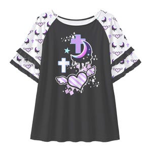 May include: A black raglan shirt with white tiered bell sleeves featuring a repeating pattern of purple crescent moons and winged hearts. The centre graphic displays a purple dripping crescent moon, two light blue crosses, and a striped winged heart.