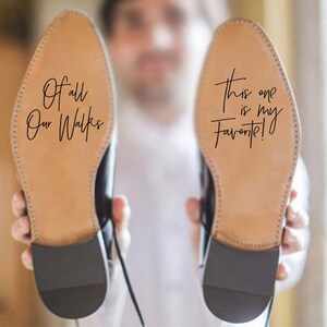 May include: A pair of brown leather shoes with black soles. The soles of the shoes have handwritten messages on them. One shoe says "Of all our walks" and the other shoe says "This one is my favourite!"