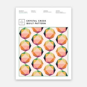 Puede incluir: Un papel blanco con un borde verde presenta un patrón de edredón geométrico. El patrón consiste en formas de diamante multicolores repetidas en tonos de naranja, rosa, verde y morado. Se muestra el texto "Crystal Creek Quilt Pattern".