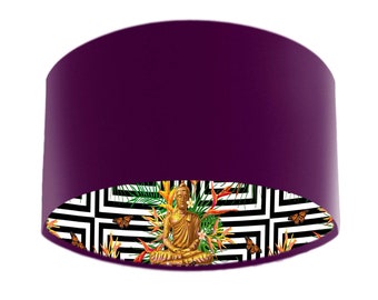 May include: A purple lampshade with a black and white geometric pattern and a gold Buddha statue sitting in the center. The pattern includes tropical leaves and butterflies.