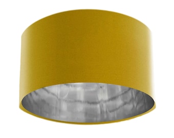 May include: A round, yellow lampshade with a silver lining. The lampshade is made of fabric and has a textured surface.