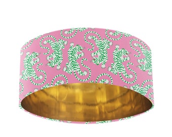 May include: A pink lampshade with a white and green tiger print. The inside of the lampshade is gold.
