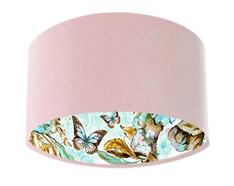 May include: A pink fabric lampshade with a white and blue floral and butterfly design on the inside.