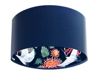 May include: A navy blue lampshade with a floral print lining. The print features white cranes, red and orange flowers, and green leaves on a dark blue background.