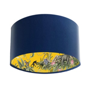 May include: A blue lampshade with a yellow and white tropical print on the inside. The print features monkeys, an elephant, and palm trees.