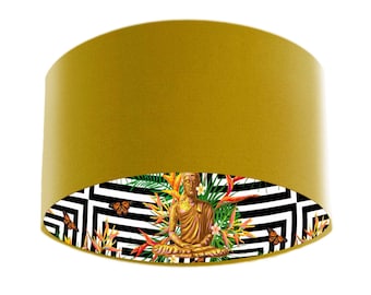 May include: A mustard yellow lampshade with a black and white geometric pattern and a gold Buddha statue sitting in the center. The pattern includes tropical leaves and butterflies.
