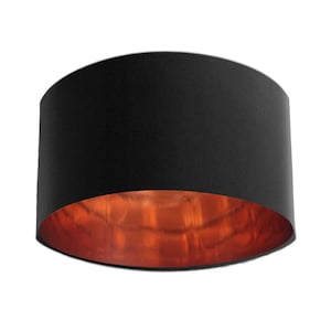May include: Black lampshade with a copper interior. The lampshade is round and has a smooth surface.