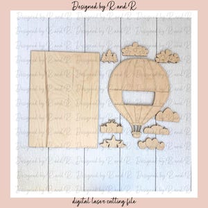 May include: A digital laser cutting file design for a hot air balloon with clouds, stars, and a gift box. The design is on a wood background.