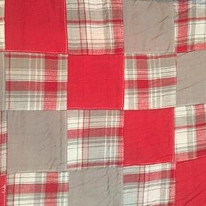 May include: A patchwork quilt with squares of red and plaid fabric. The quilt is made of different shades of red and gray.