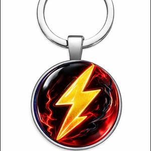 Puede incluir: Un llavero plateado con un colgante redondo. El colgante muestra un rayo amarillo sobre un fondo rojo y negro. El rayo está centrado, con un llavero plateado en la parte superior.