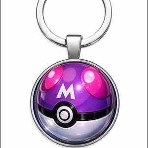 Puede incluir: Un llavero plateado con un colgante morado y blanco. El colgante presenta una esfera morada con detalles rosas y un símbolo "M" blanco. La mitad inferior es blanca con un círculo negro.
