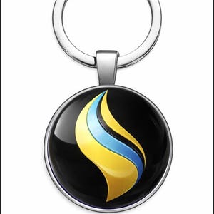 Puede incluir: Un llavero redondo con un diseño de llama en amarillo y azul sobre un fondo negro. El colgante tiene un borde de metal plateado y un llavero plateado.