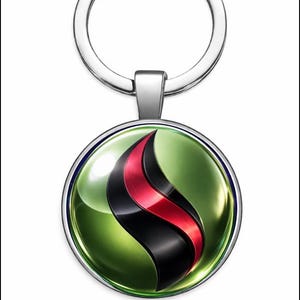 Puede incluir: Un llavero plateado con un colgante circular. El colgante presenta un fondo verde con un diseño de llama negro y rojo. El llavero tiene un anillo para sujetar llaves.