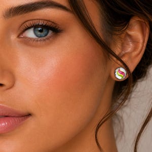 May include: A circular stud earring featuring a white base with a swirling pattern of bright pink and lime green lines. The earring is small and round, designed to sit flush against the earlobe, showcasing a smooth, polished surface finish.