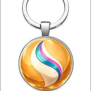 Puede incluir: Un llavero plateado con un colgante redondo. El colgante presenta un fondo dorado y un diseño abstracto blanco, turquesa y rosa. El llavero tiene un anillo plateado para sujetar llaves.