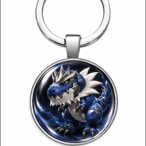 Puede incluir: Un llavero plateado con un colgante redondo que presenta un diseño de dragón azul y blanco. El dragón tiene una apariencia detallada y texturizada con garras afiladas y una melena puntiaguda. El fondo es un patrón azul arremolinado.