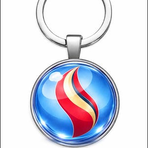 Puede incluir: Un llavero plateado con un colgante redondo. El colgante tiene un fondo azul y un diseño de llama estilizada en rojo, amarillo y blanco. El llavero tiene un anillo partido para llaves.