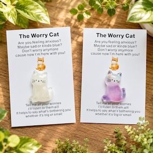 May include: Two white display cards titled The Worry Cat, each featuring a small cat figurine. One card holds a translucent white cat, the other a purple and blue gradient cat. Both cards include printed text about sharing worries and feelings.